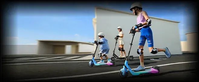Trois enfants casqués et protégés roulent sur des trottinettes Navee K100 sur une esplanade goudronnée