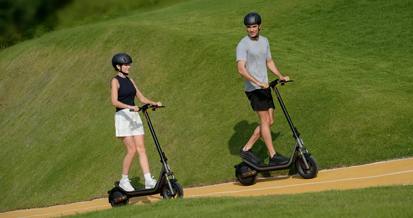 Deux conducteurs casqués sur des Xiaomi Electric Scooter 6 le long d'un chemin au pied d'une colline